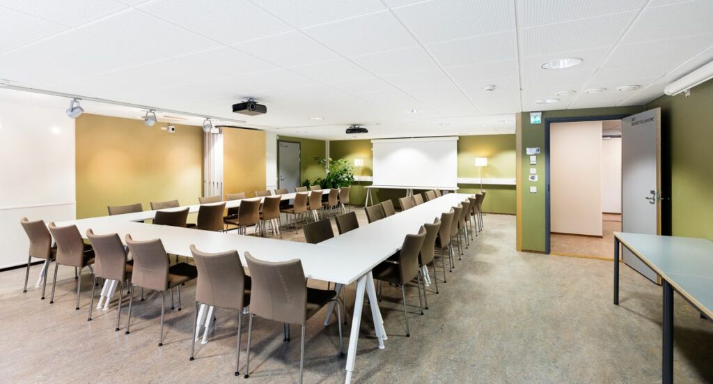 Kokoustila, jossa on valkoiset pöydät.